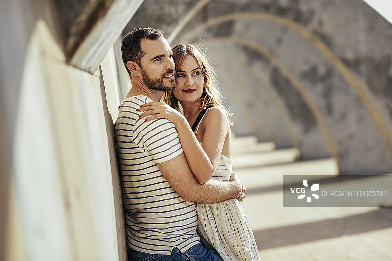 西班牙安达卢西亚马拉加亲密的游客情侣在拱门下拥抱图片素材