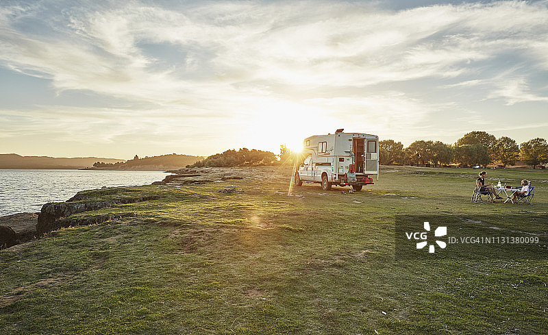 智利塔尔卡，马乌莱河，露营者在湖边与家人共进日落晚餐图片素材