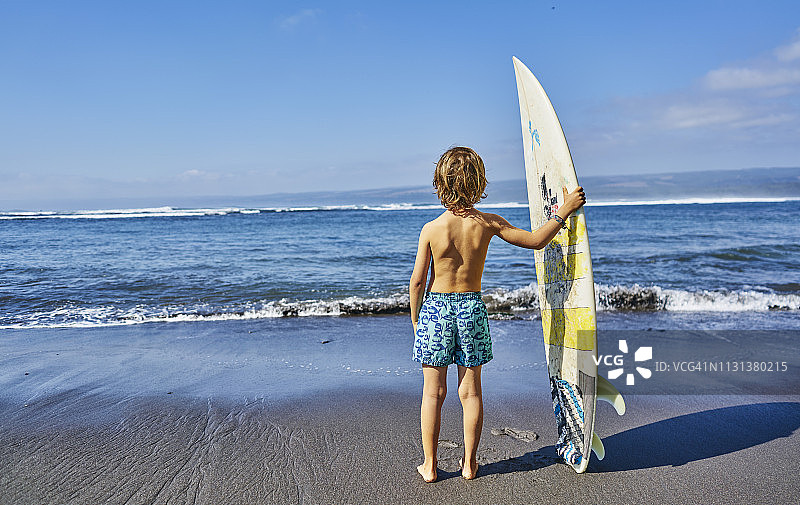 智利皮奇莱穆：站在海边拿着冲浪板的男孩图片素材