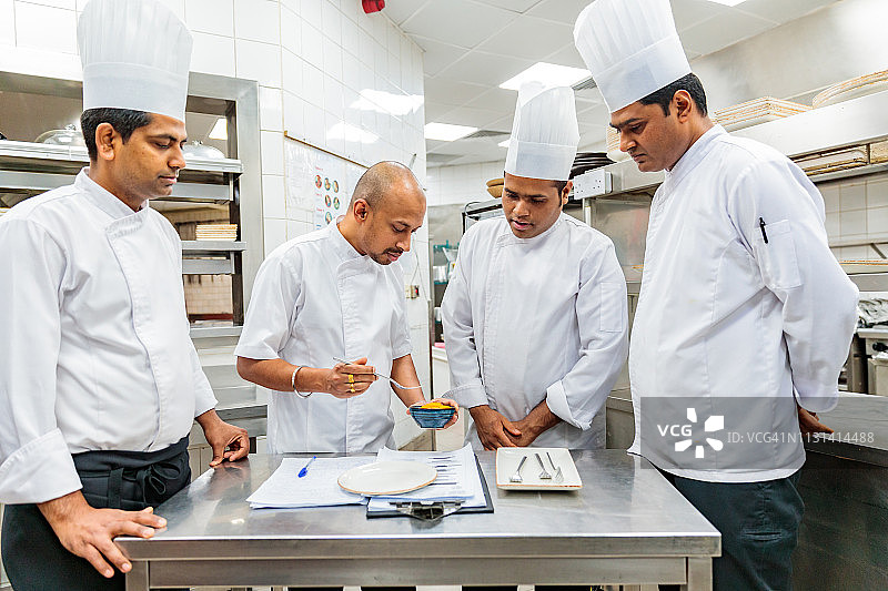 行政主厨和他的厨房工作人员一起品尝食谱图片素材