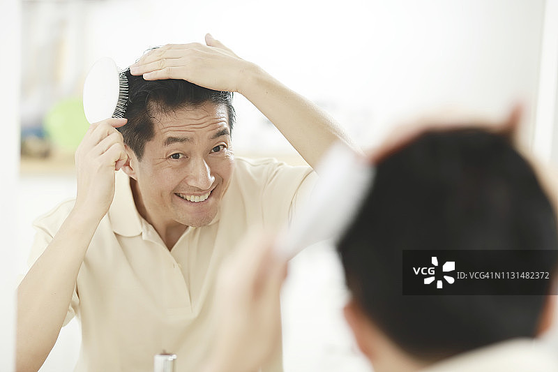 在镜子前梳头的中年男人图片素材