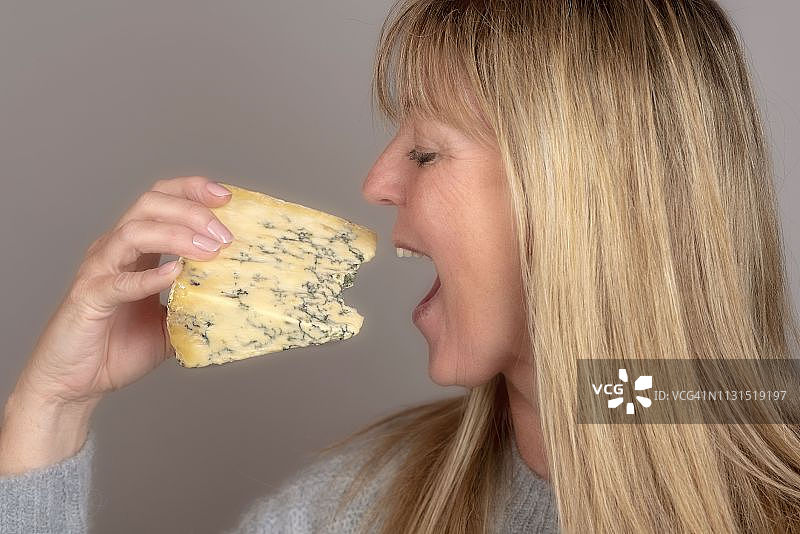 金发女人正在享用蓝纹奶酪图片素材