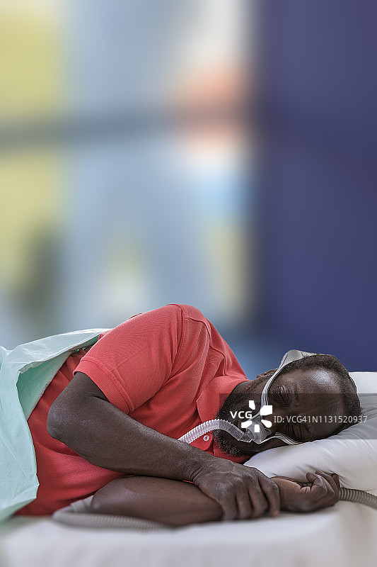 男人使用CPAP呼吸机面罩治疗睡眠呼吸暂停综合征图片素材