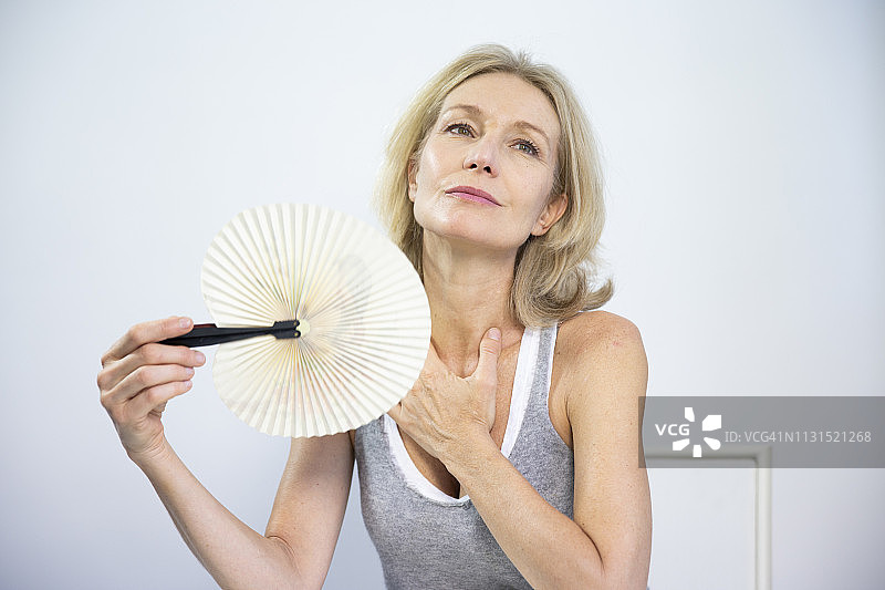 女人扇着扇子缓解潮热症状图片素材