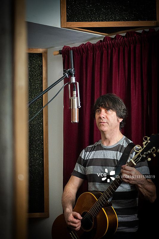 男性音乐家弹奏原声吉他的录音棚人像图片素材