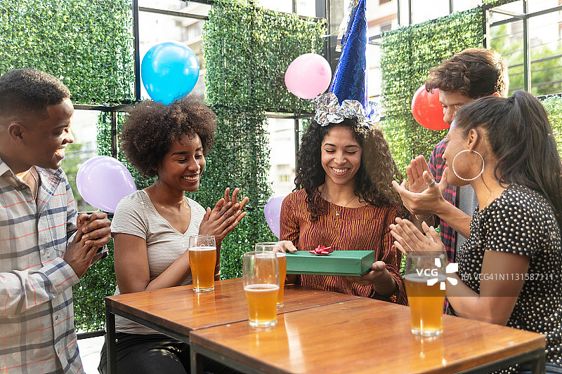 一群不同种族的朋友庆祝生日，一位女士正在打开礼物图片素材