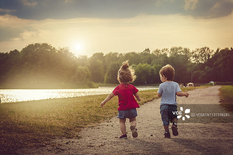 在夏日落日下户外玩耍的可爱男孩和女孩图片素材