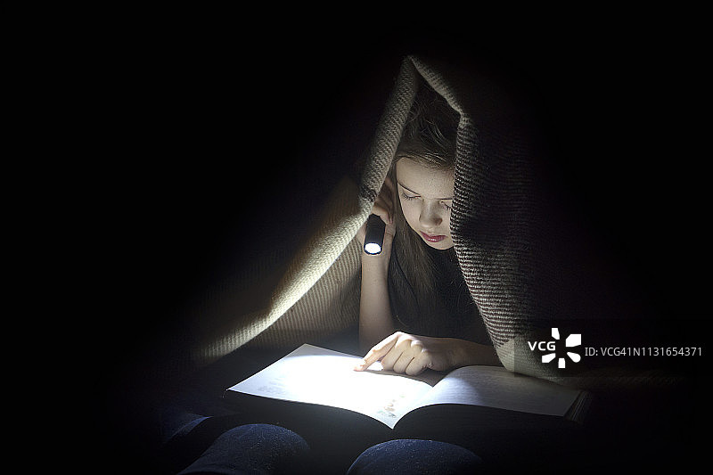 用手电筒看书的女孩图片素材