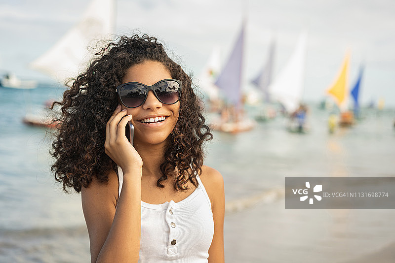 女孩在海滩上打电话图片素材