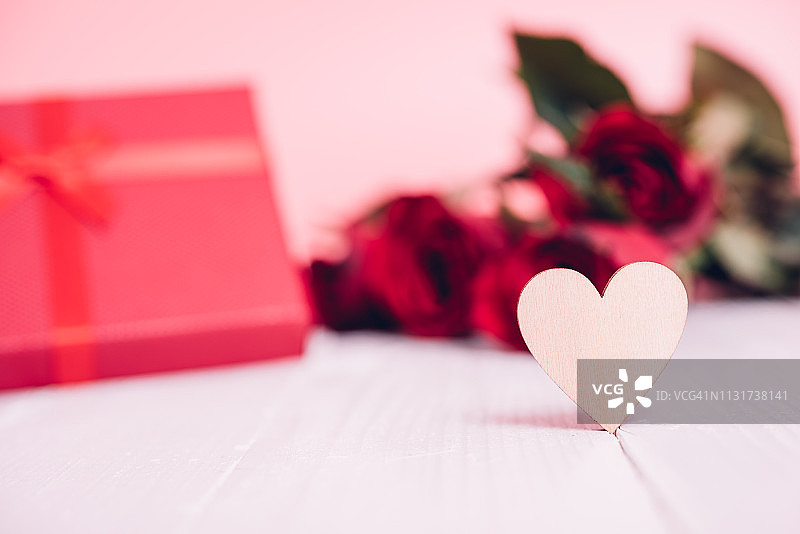 白色木质上的木制心形，有红色玫瑰花和礼品盒图片素材