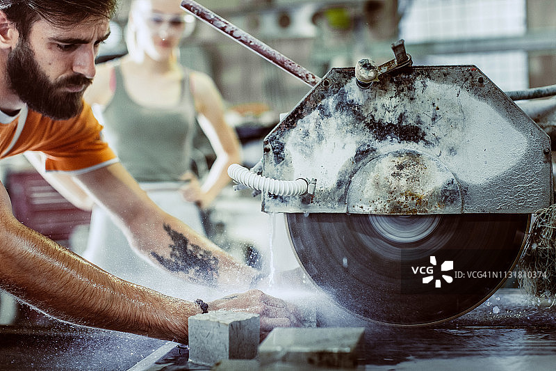 年轻男人用圆锯切割石头图片素材