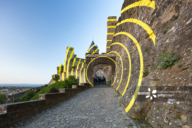 瑞士艺术家费利切·瓦里尼在法国卡尔卡松城墙上的黄色圆形条纹作品，2018年4月图片素材