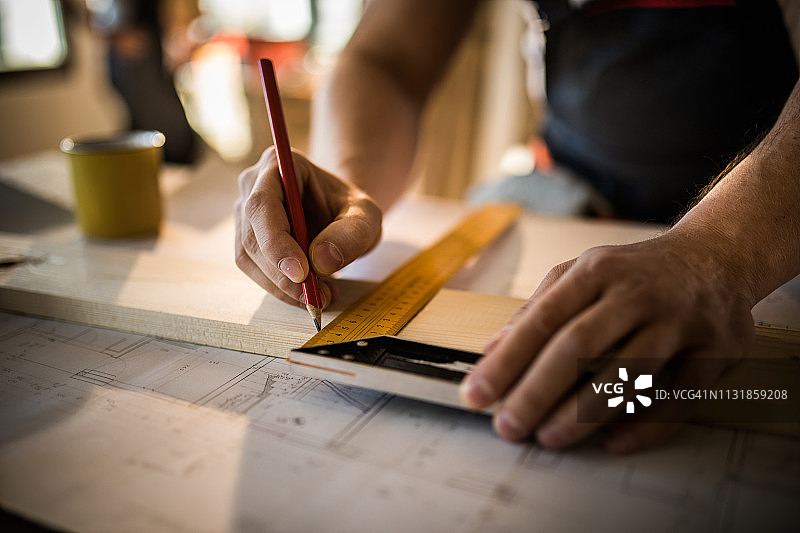 一位木匠在木板上进行测量和绘图的特写图片素材