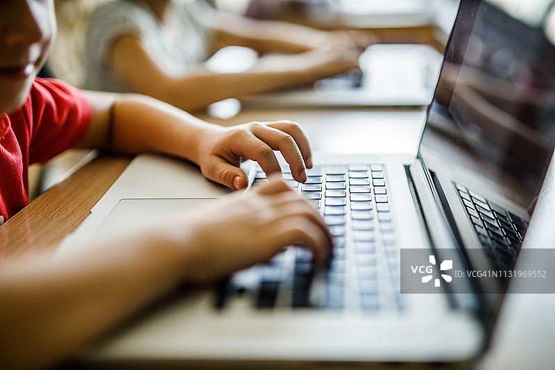 在学校用笔记本电脑打字的儿童特写图片素材