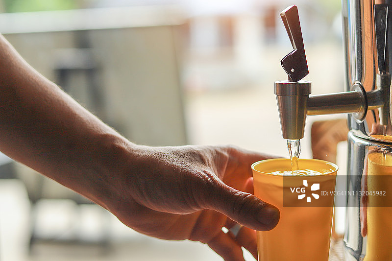 男人用塑料杯盛饮水机里的水图片素材