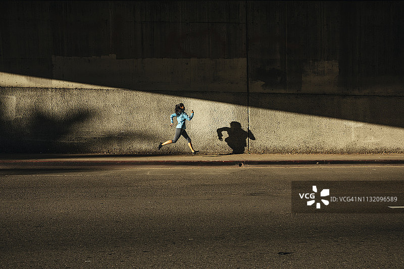 在城市街道上靠墙奔跑的女人图片素材