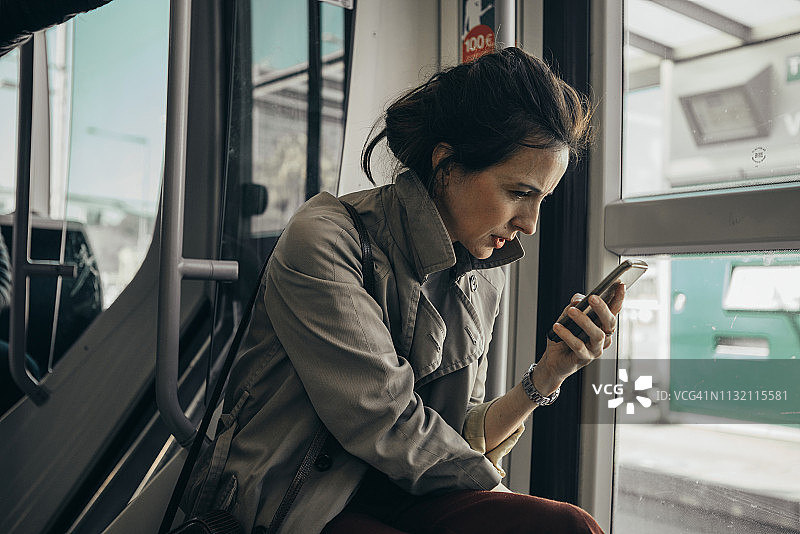 女人在有轨电车上用手机聊天图片素材