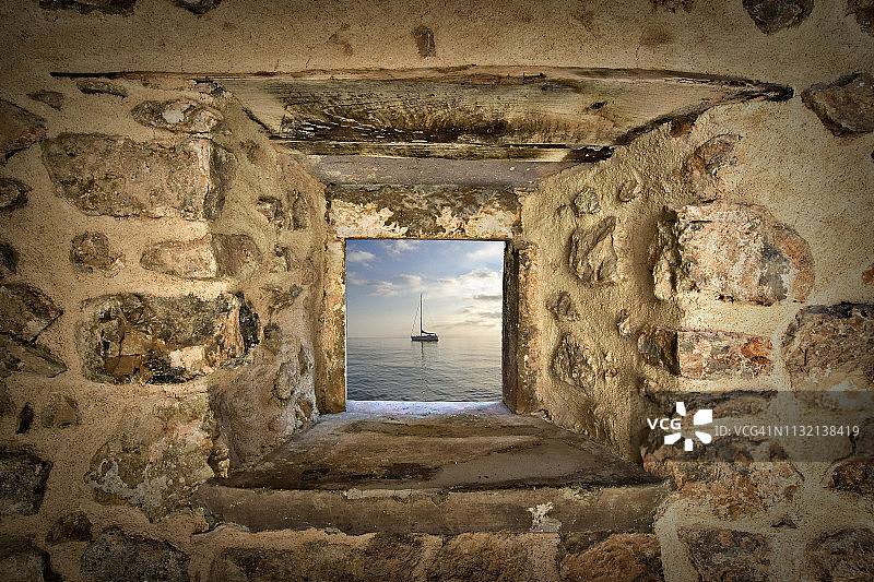 透过石墙窗户看到的翡翠海上帆船图片素材