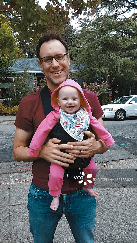 骄傲的父亲在户外人行道上抱着微笑的新生婴儿图片素材