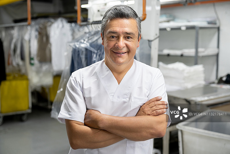 自信的男经理在洗衣店面对镜头，双臂交叉图片素材