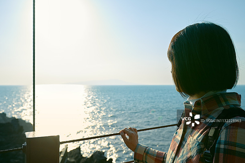 日本女人在旅途中欣赏海上风光，站在悬索桥上图片素材