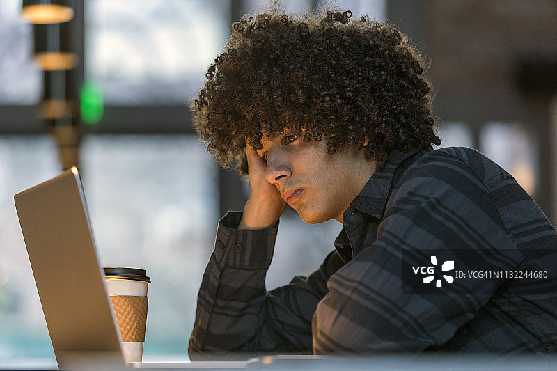 在咖啡馆里使用笔记本电脑的青少年男孩图片素材