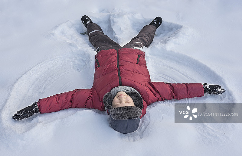 男孩在雪地里制作雪天使图片素材