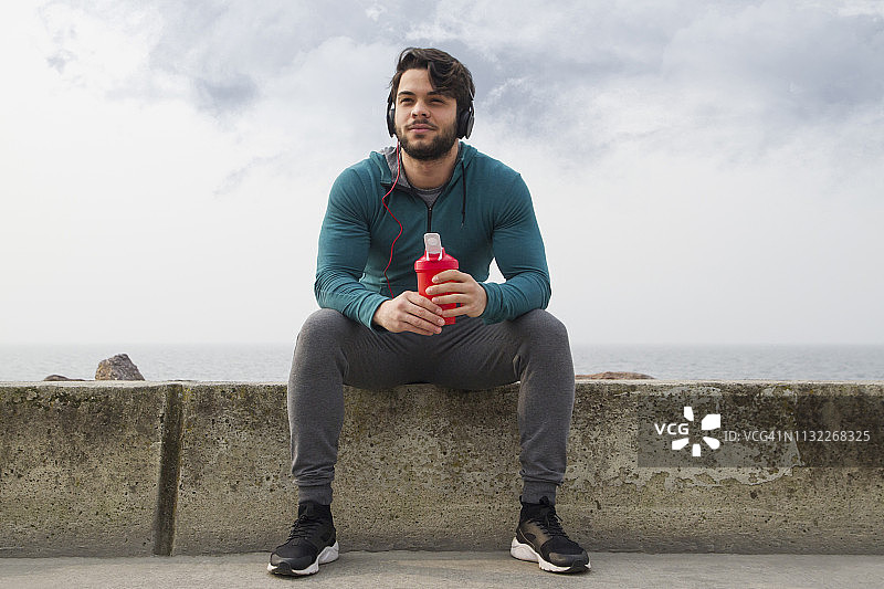 在雾天户外锻炼后，年轻男子喝他的蛋白奶昔图片素材
