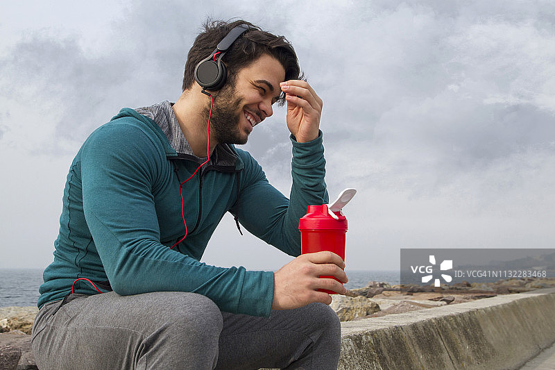 在雾天户外锻炼后，年轻男子喝他的蛋白奶昔图片素材