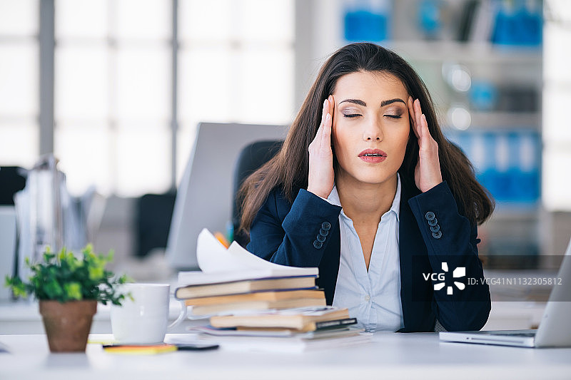 有压力的女商人因头痛在办公室感到痛苦图片素材