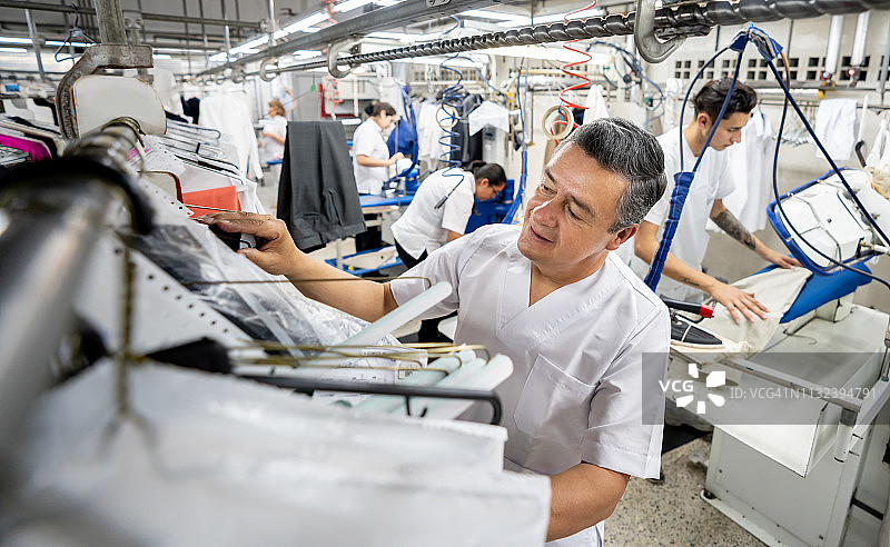 在洗衣店的架子上寻找衣服的拉丁美洲男子图片素材