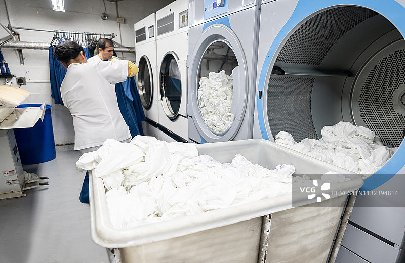 在洗衣服务店一起搬运洗衣机的拉美男人们图片素材