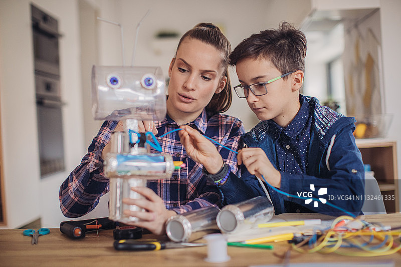 女老师和男孩一起组装机器人图片素材