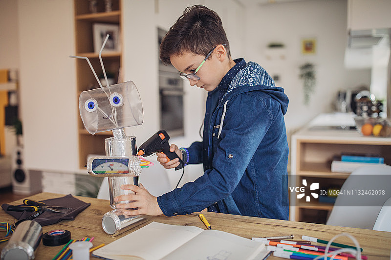男孩在家构建机器人，用于学校科学项目图片素材