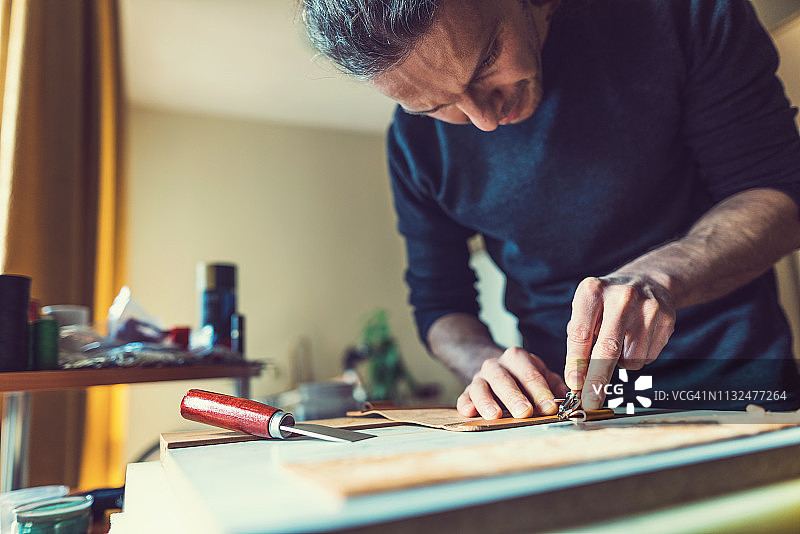 在工作台上制作皮夹的男人图片素材