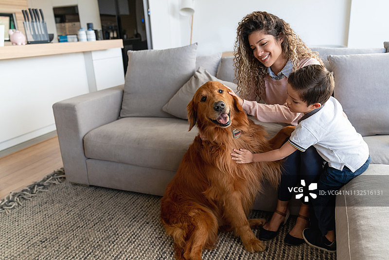 快乐的母亲和儿子在家抚摸他们的狗图片素材