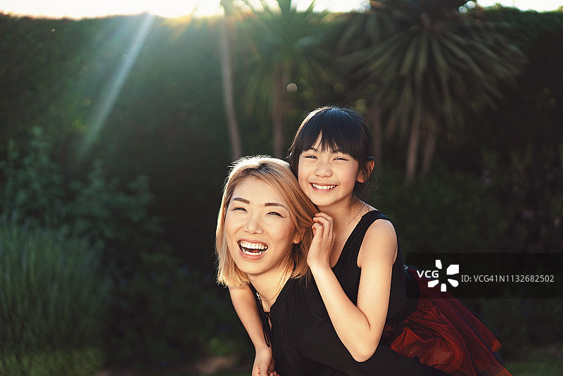 快乐的母亲在院子里背着女儿图片素材