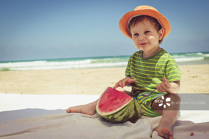 在海滩上吃西瓜的可爱快乐的孩子图片素材