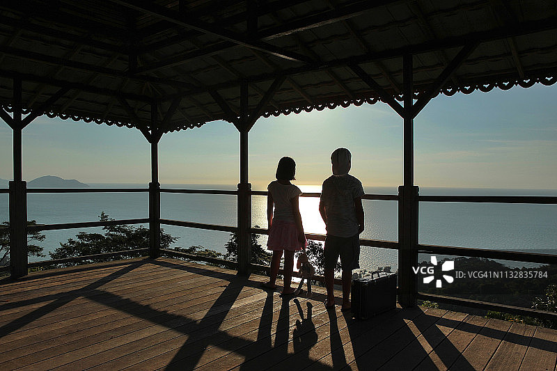 男孩和女孩站在凉亭里看海景的剪影图片素材
