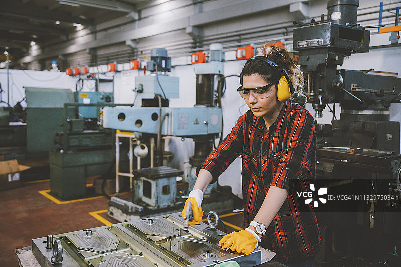 年轻女车床工人在工厂使用吹风枪工作图片素材
