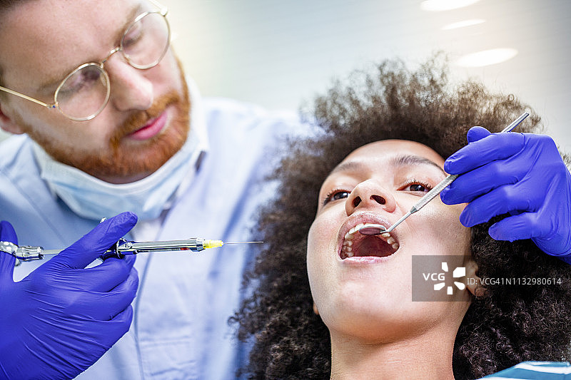 医生用注射器为患者进行牙科局部麻醉。图片素材