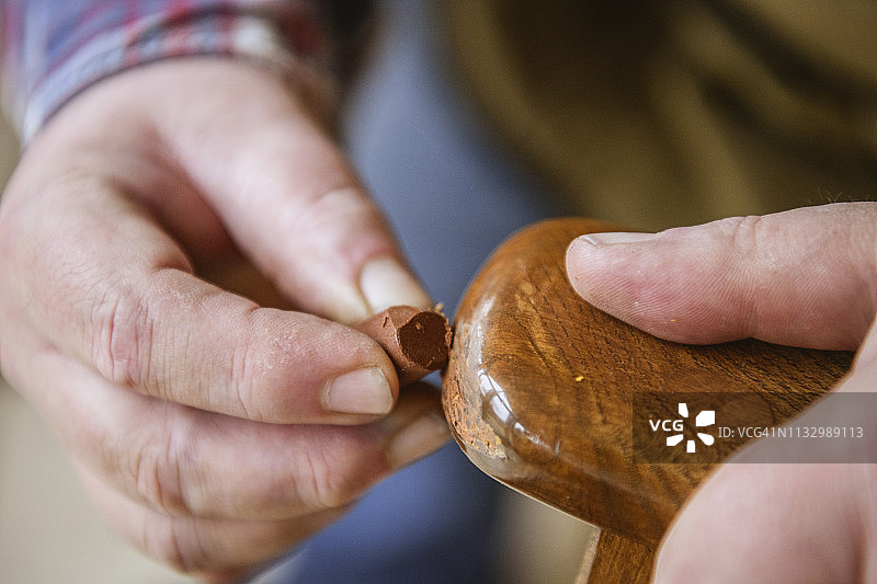 男子在椅子扶手上涂棕色蜡特写图片素材