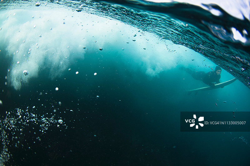 冲浪者在海浪下带着冲浪板游泳图片素材