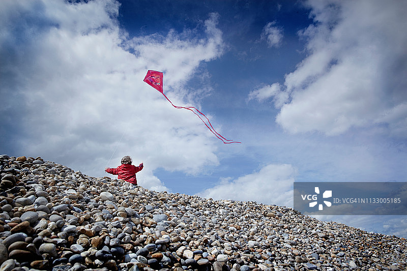 小男孩在鹅卵石海滩上放风筝图片素材
