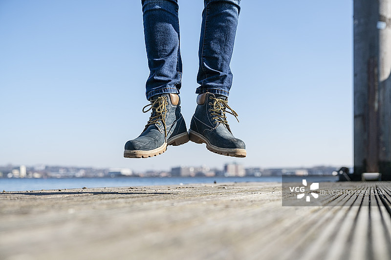 在德国阳光明媚的日子里，男人在码头上跳跃的下半身图片素材