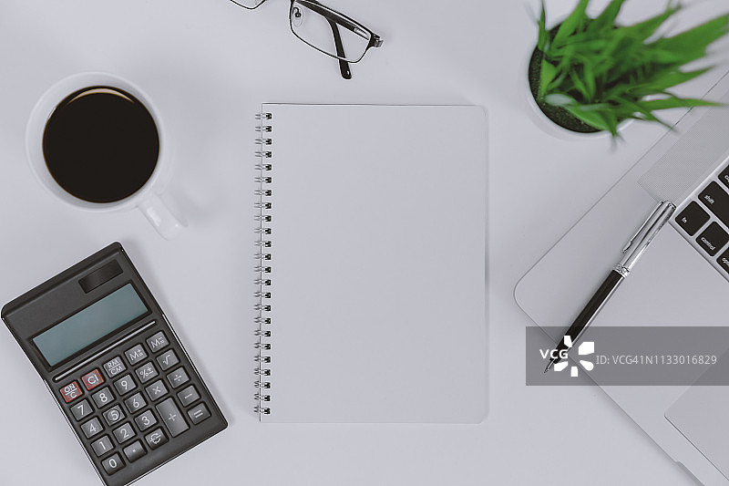 办公桌上的空白便笺簿、笔记本电脑和计算器图片素材