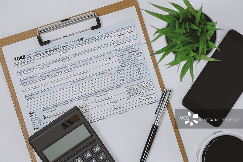 工作桌上的剪贴板上的税务表格、计算器和手机图片素材