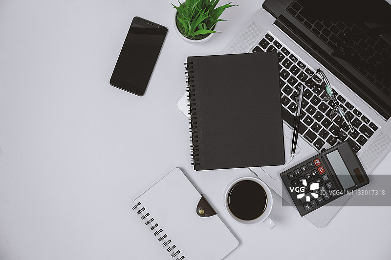 办公桌上的黑色螺旋笔记本、笔记本电脑和计算器图片素材