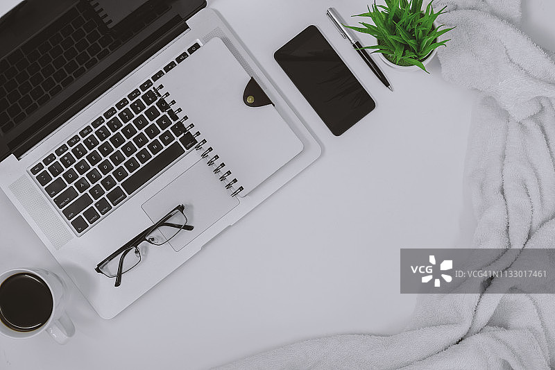 舒适的办公桌上的笔记本电脑、记事本和手机图片素材