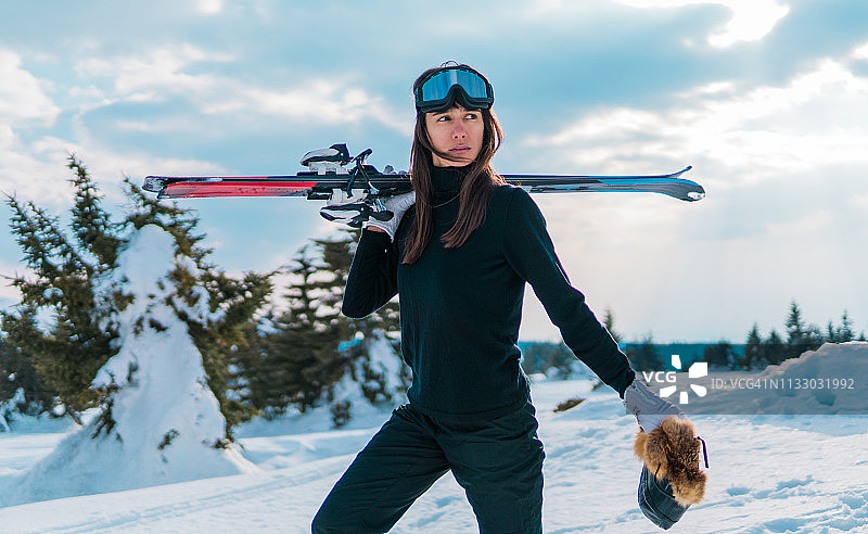 在山中拿着滑雪板行走的女人图片素材